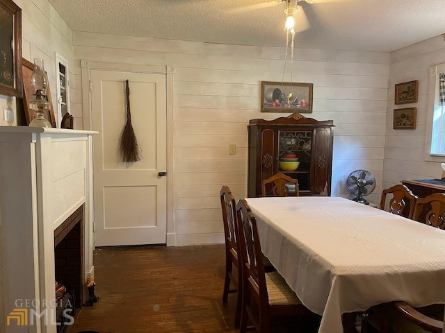 dining room with wooden walls, dark hardwood / wood-style flooring, a textured ceiling, and ceiling fan