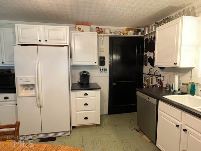 kitchen featuring white refrigerator with ice dispenser, tasteful backsplash, dishwasher, and white cabinetry