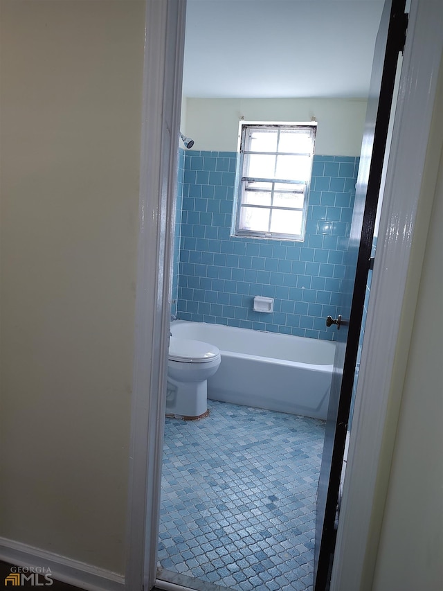 bathroom with toilet, tile floors, and tiled shower / bath combo