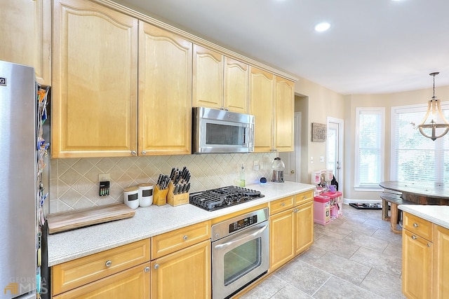 kitchen featuring appliances with stainless steel finishes, a notable chandelier, tasteful backsplash, and decorative light fixtures