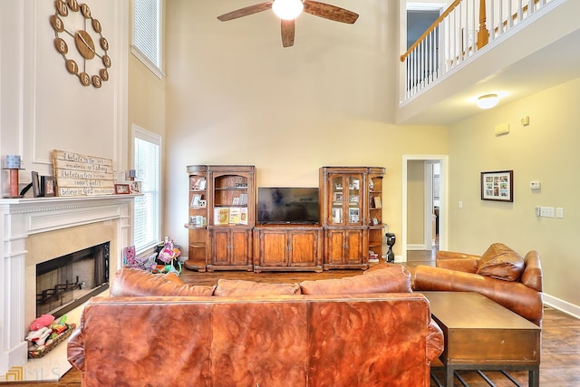 living room with dark tile flooring, a fireplace, ceiling fan, and a high ceiling