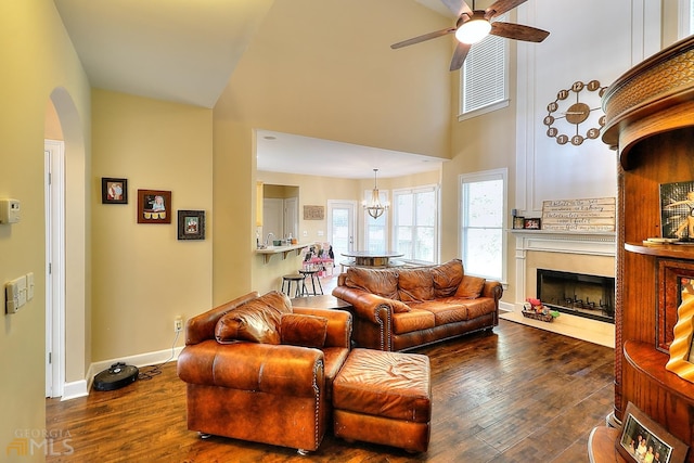 living room with dark hardwood / wood-style floors, ceiling fan with notable chandelier, and a towering ceiling