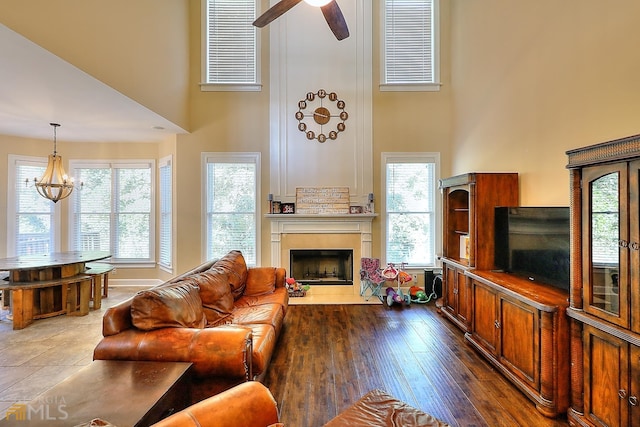 living room featuring tile floors, a high ceiling, and ceiling fan with notable chandelier