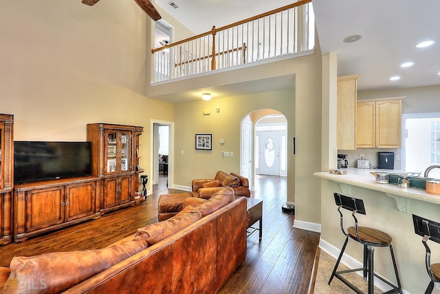 living room featuring a high ceiling, ceiling fan, and dark hardwood / wood-style flooring