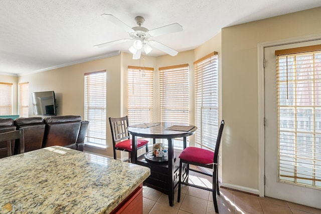 dining space featuring light tile flooring, ornamental molding, ceiling fan, and a textured ceiling