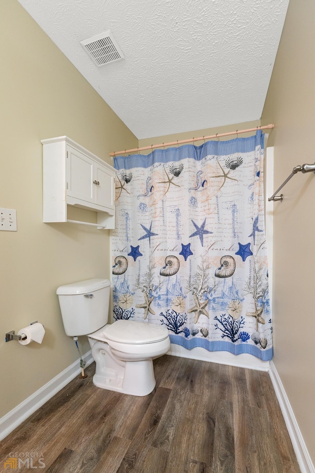 bathroom with a textured ceiling, toilet, and hardwood / wood-style flooring