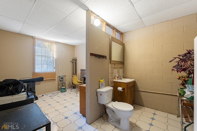 bathroom featuring tile walls, toilet, a paneled ceiling, tile floors, and large vanity