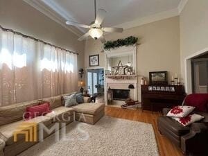 living room with hardwood / wood-style floors, ceiling fan, and crown molding