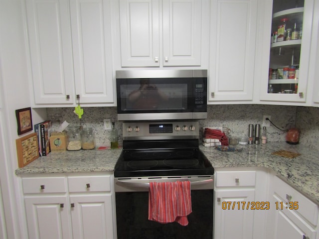 kitchen with white cabinets, backsplash, appliances with stainless steel finishes, and light stone counters