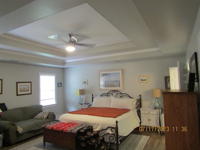 bedroom with a tray ceiling, ceiling fan, wood-type flooring, and crown molding