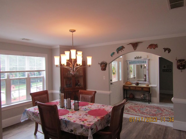 dining space with a notable chandelier, ornamental molding, and light hardwood / wood-style flooring