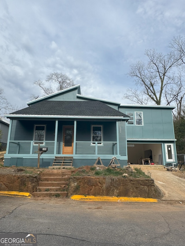 view of front of house with a garage, driveway, a porch, and a shingled roof