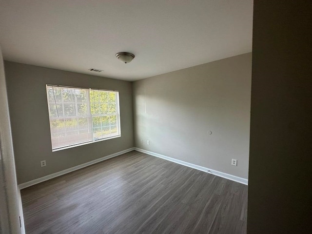 unfurnished room with dark wood-type flooring