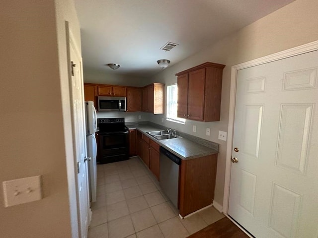 kitchen with appliances with stainless steel finishes, light tile floors, and sink