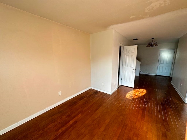 spare room featuring a chandelier and dark hardwood / wood-style flooring