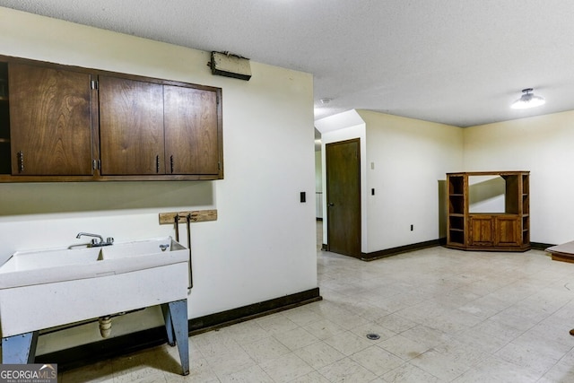 washroom with sink, a textured ceiling, and light tile floors