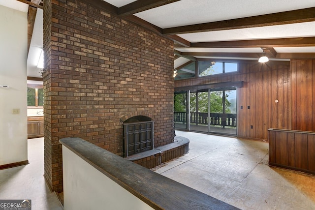 sitting room featuring beamed ceiling, light carpet, and brick wall