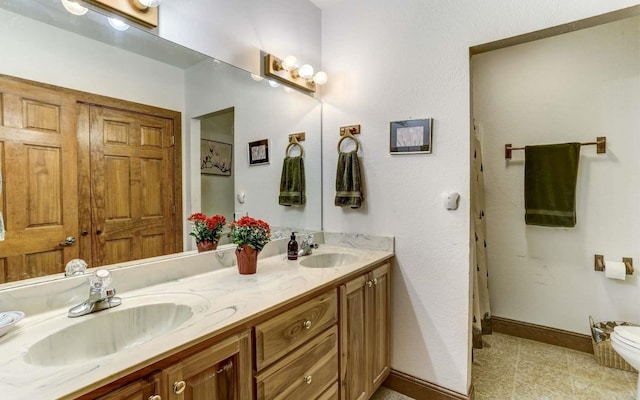 bathroom featuring tile floors, toilet, and dual bowl vanity