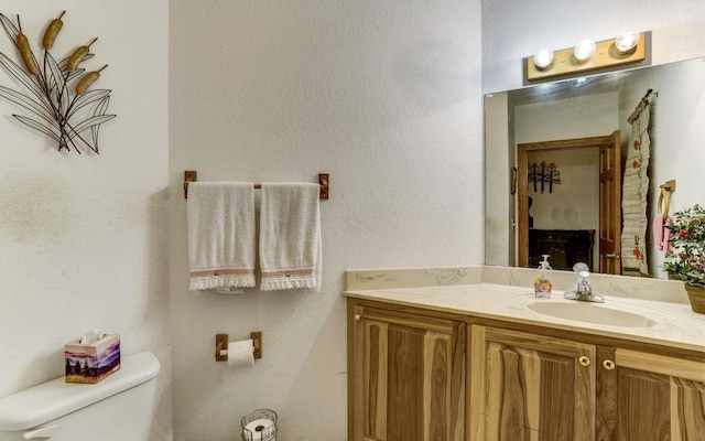 bathroom with toilet and vanity with extensive cabinet space