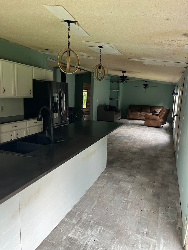 kitchen featuring wood-type flooring, sink, decorative light fixtures, white cabinetry, and a textured ceiling