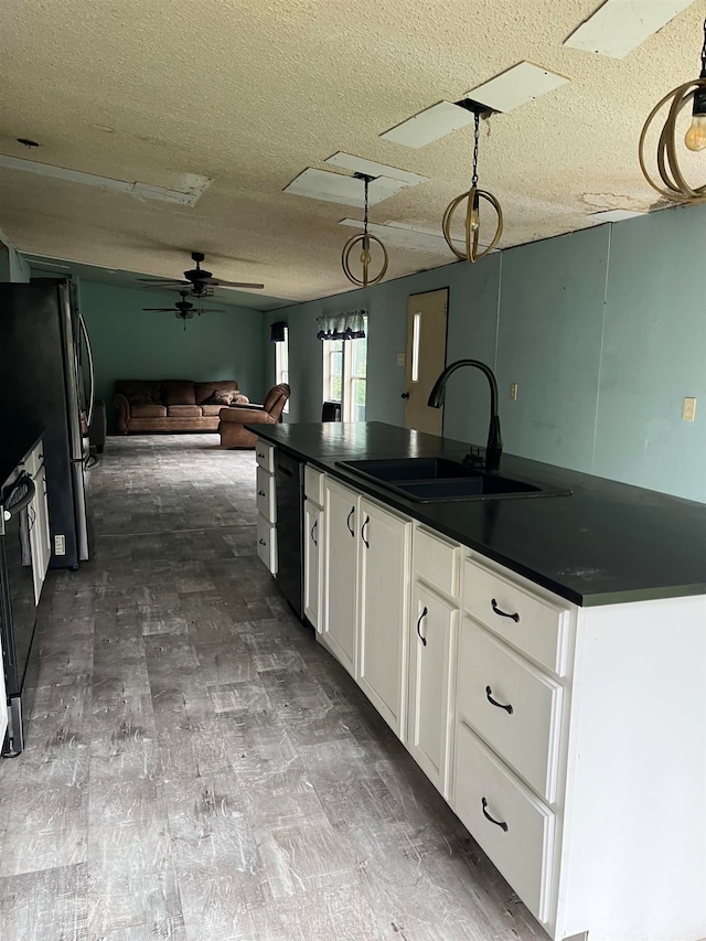 kitchen featuring sink, a textured ceiling, pendant lighting, white cabinets, and stainless steel refrigerator