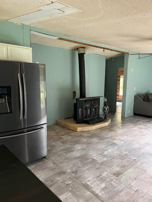 kitchen featuring a healthy amount of sunlight, stainless steel fridge, a textured ceiling, and a wood stove