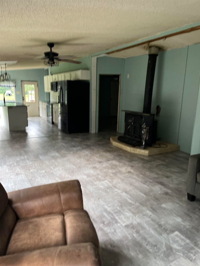 living room with a textured ceiling, a wood stove, and ceiling fan