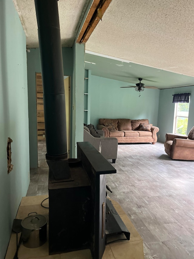 living room featuring a wood stove, a textured ceiling, and ceiling fan