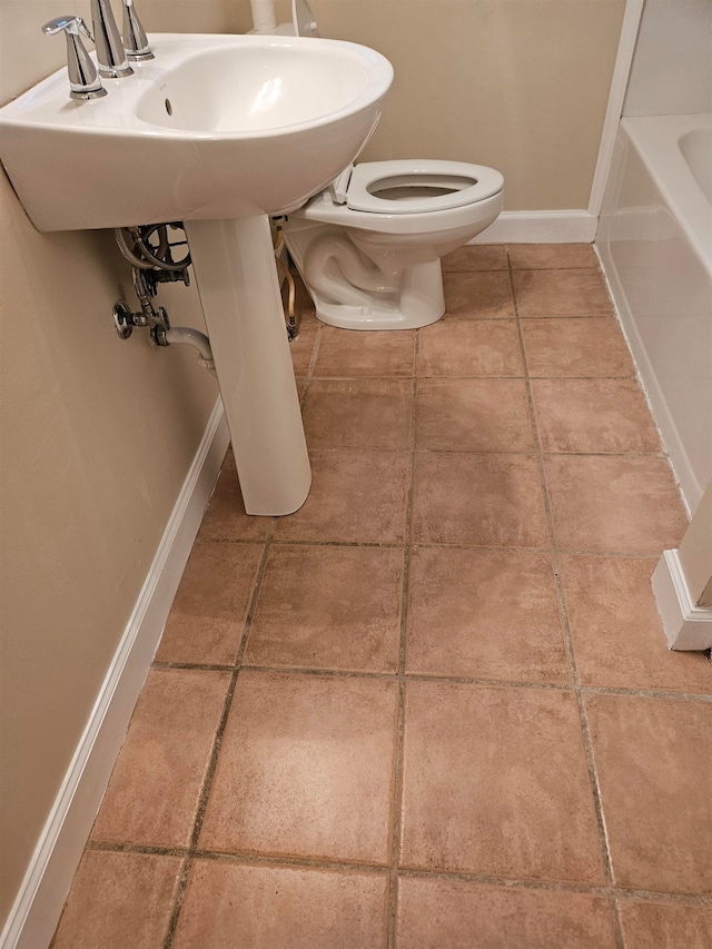 bathroom with tile patterned flooring, toilet, and a bathing tub