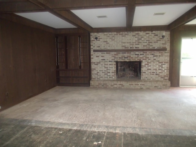 unfurnished living room with beamed ceiling, a fireplace, and wooden walls