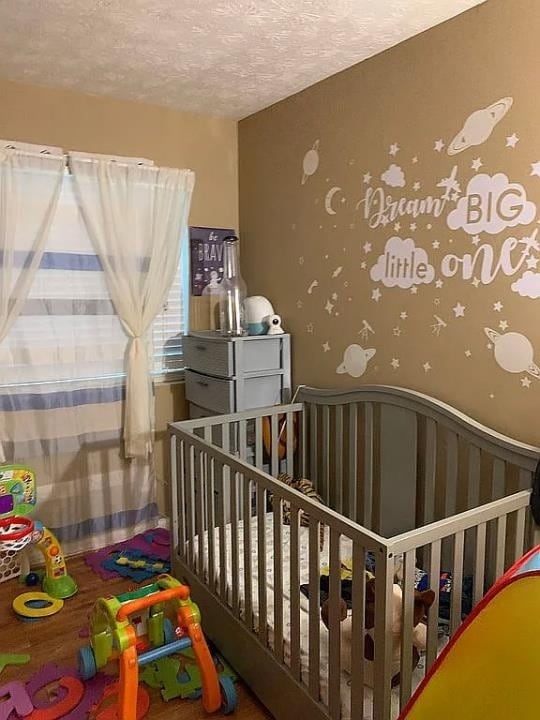 bedroom featuring a crib and a textured ceiling