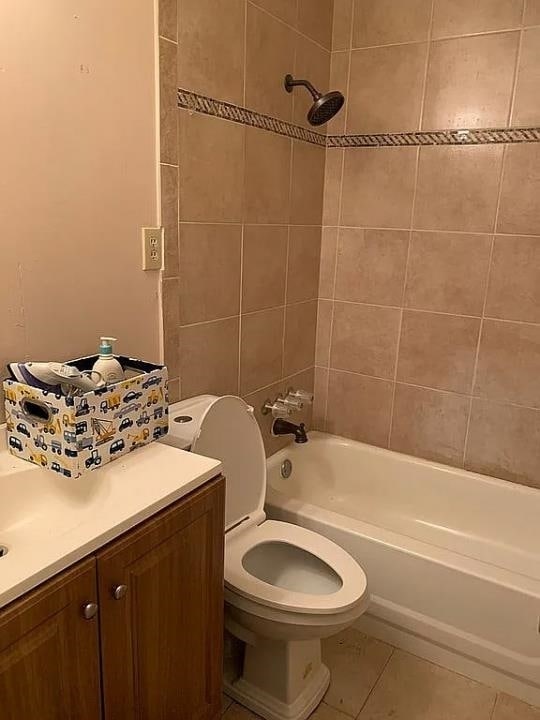 full bathroom featuring toilet, vanity, tiled shower / bath, and tile flooring