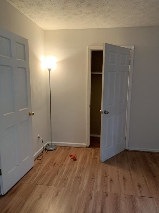 unfurnished bedroom featuring a closet, light hardwood / wood-style floors, and a textured ceiling