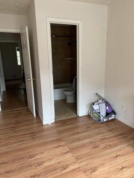 unfurnished bedroom featuring light tile flooring, a closet, connected bathroom, and a spacious closet