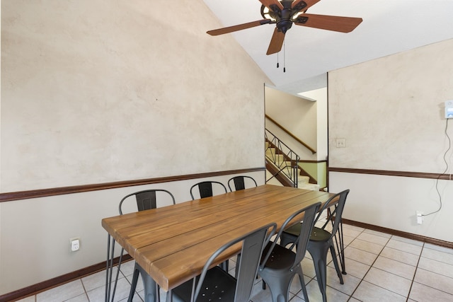 dining room with ceiling fan, vaulted ceiling, and light tile floors