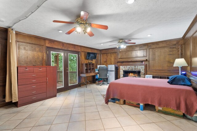 bedroom with wood walls, a fireplace, ceiling fan, stainless steel fridge, and access to outside