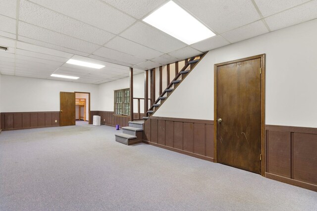 basement featuring a paneled ceiling and light colored carpet