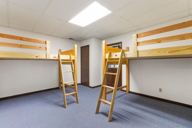 unfurnished bedroom with a drop ceiling and dark colored carpet