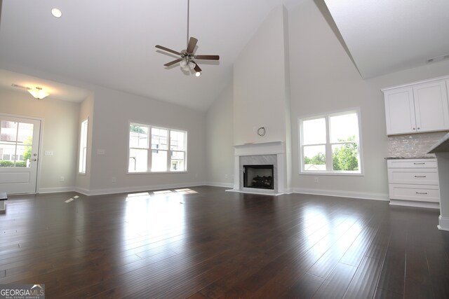 unfurnished living room with high vaulted ceiling, ceiling fan, dark hardwood / wood-style floors, and a premium fireplace