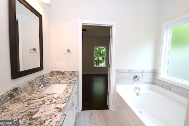 bathroom with a washtub, tile floors, and large vanity