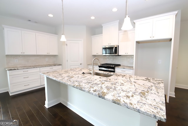 kitchen featuring appliances with stainless steel finishes, tasteful backsplash, dark hardwood / wood-style flooring, a center island with sink, and pendant lighting