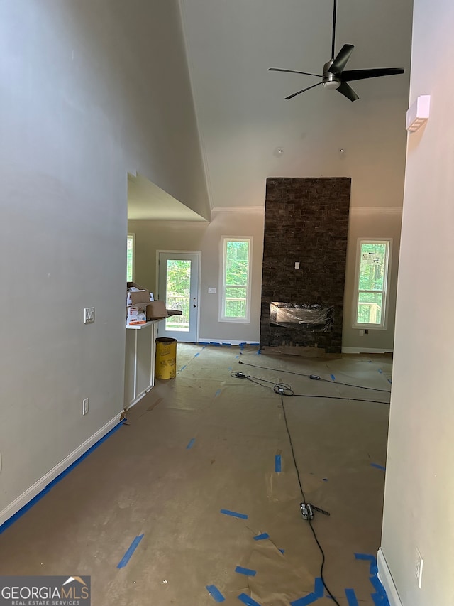 unfurnished living room featuring a high ceiling, ceiling fan, and a fireplace