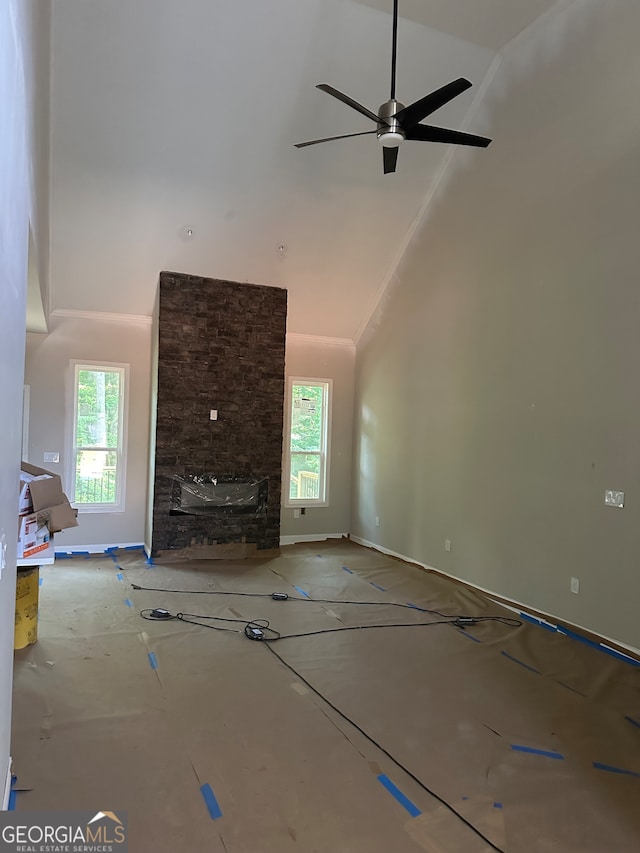 unfurnished living room with high vaulted ceiling, ceiling fan, and a stone fireplace