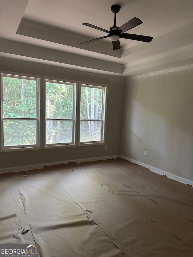 empty room featuring a tray ceiling and ceiling fan