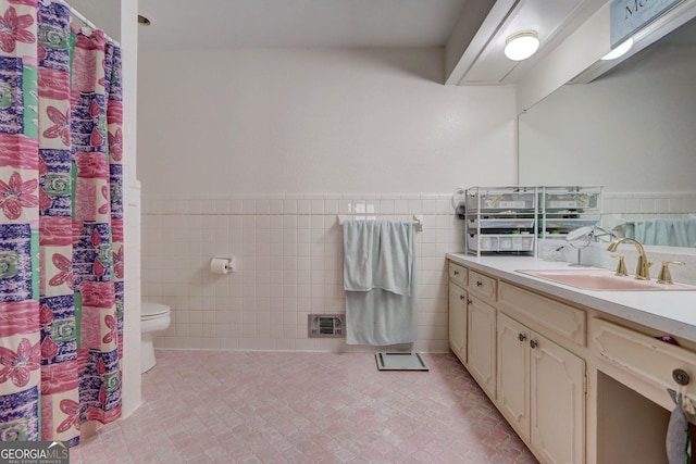 bathroom featuring toilet, vanity, tile walls, and tile patterned floors