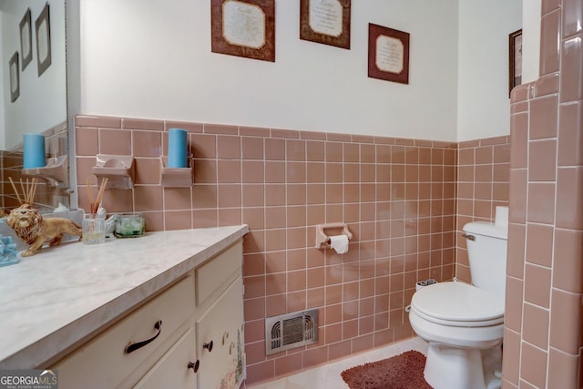 bathroom featuring toilet, tile walls, tile patterned floors, and vanity