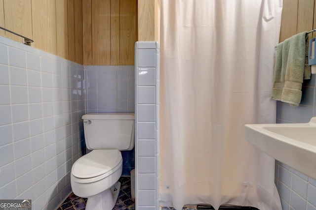 bathroom with tile walls and toilet