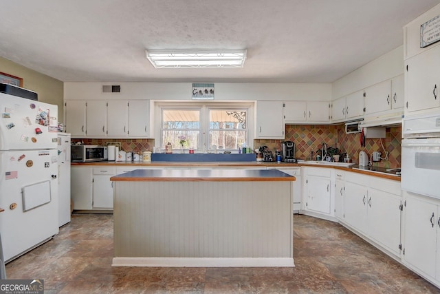 kitchen featuring white cabinetry, sink, white appliances, and a kitchen island