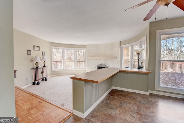 kitchen featuring a brick fireplace, a kitchen bar, kitchen peninsula, and ceiling fan