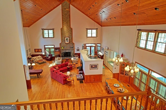 living room featuring light wood-type flooring, a fireplace, wood ceiling, high vaulted ceiling, and a chandelier